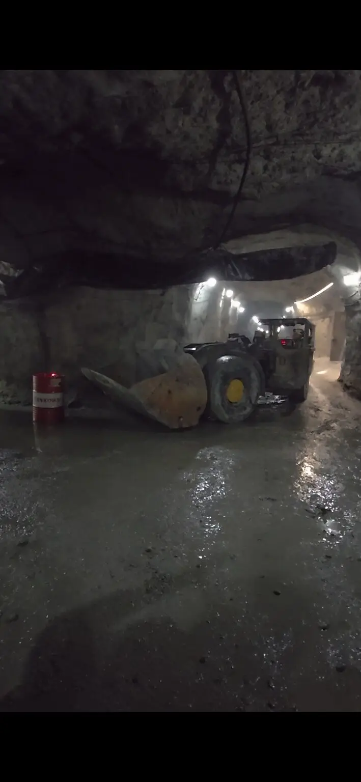 Underground loader with its bucket lowered in a lit drive